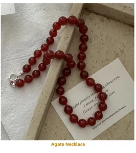 Detail of red agate bead necklace with silver spring clasp on a ceramic tray