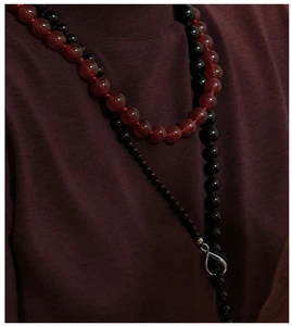Detail of red agate and black beads necklace with silver infinity symbol pendant