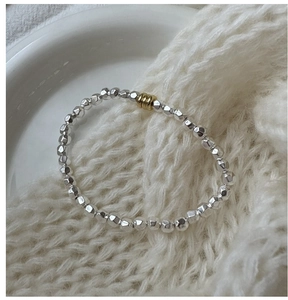 Close-up of S925 sterling silver beaded bracelet with a gold accent on knit fabric