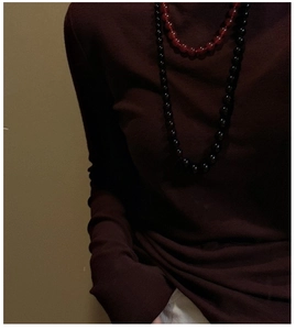 Detail of red agate beaded necklace styled on burgundy knit turtleneck long sleeve top