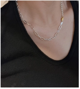 Detail of silver paperclip chain necklace with gold clasp on model wearing black