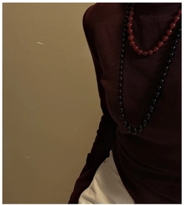 Detail of red agate beaded necklace layered over a dark burgundy turtleneck knit sweater