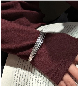 Italian multilayer S925 silver bracelet styled over red sleeve with vintage book