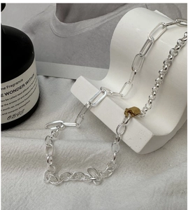 Detail of S925 silver mixed-link necklace with golden clasp on ceramic stand