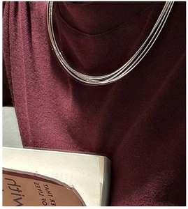 Close-up of triple-layered silver choker necklace on a burgundy knit sweater model