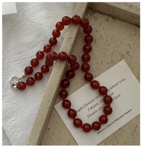 Detailed shot of red agate beaded necklace with silver clasp on minimalist tray
