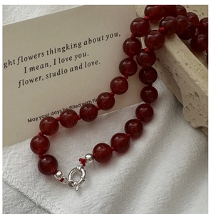 Detail of red agate beads with S925 silver clasp on rustic stone and fabric background