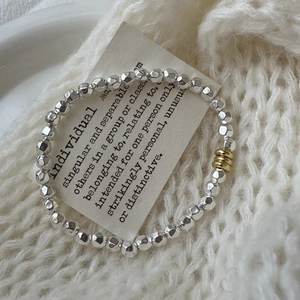 Minimalist S925 silver beaded bracelet with gold accents on white knit background
