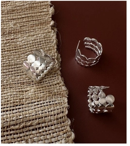 Detailed view of silver stackable earrings with textured irregular metal discs