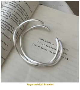 Close-up of matte S925 silver open bangle with wavy texture on an open vintage book