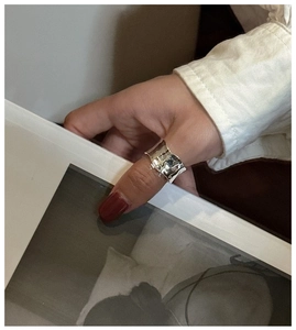 Detailed view of wide sterling silver ring with hammered texture on model thumb