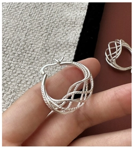 Macro detail of S925 sterling silver hoop earrings with hand-woven mesh texture