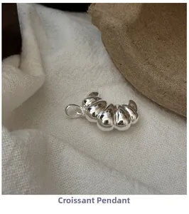 Macro shot of silver croissant pendant showing smooth metallic texture on fabric