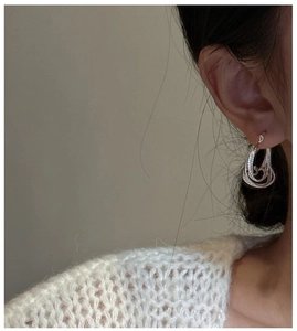 Close-up of S925 sterling silver earrings with wavy texture on a model's ear