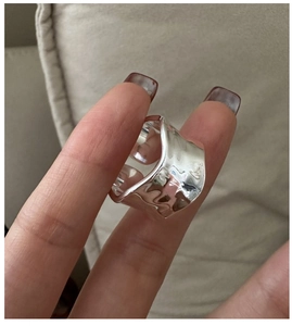 Detailed view of wide irregular wavy texture ring in polished silver finish on finger