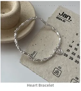 Detail of silver beaded bracelet with heart pendant on rustic ceramic decor