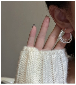 Close-up of S925 sterling silver multilayered hoop earrings on model with knit sweater