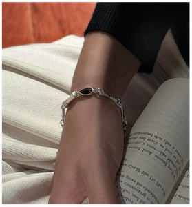 Detail of silver twisted chain bracelet with black onyx drop on a vintage book backdrop