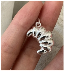Macro detail of a 925 sterling silver croissant pendant showing realistic pleated textures