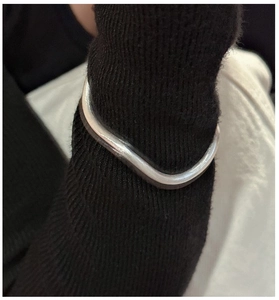Detailed view of the wavy silver bracelet with minimalist brushed texture on wrist