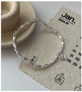 Macro detail of S925 sterling silver beaded bracelet with heart pendant on paper