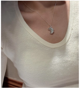 Detail shot of a silver croissant pendant necklace with polished finish on a model