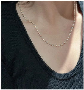 Detail of s925 silver mixed-metal beaded chain necklace on a black knit collar