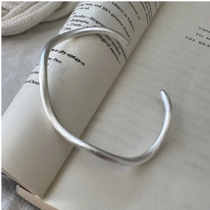 Detailed macro view of S925 sterling silver open bangle with brushed wave texture