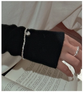 Dettaglio del bracciale di perle in argento S925 con ciondolo a cuore e anello largo inciso