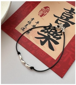 Detailed shot of a black cord bracelet with three silver beads on a festive background