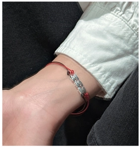 Detailed macro view of woven red and brown cord bracelet with three rows of silver beads