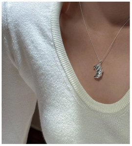 Close-up of S925 sterling silver croissant pendant on neck with elegant knitwear background