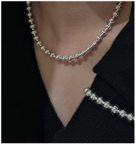Dettaglio della collana di perle in argento S925 con texture a zucca su maglione nero