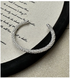 Macro detail of S925 sterling silver braided C-shape cuff bracelet with beaded texture