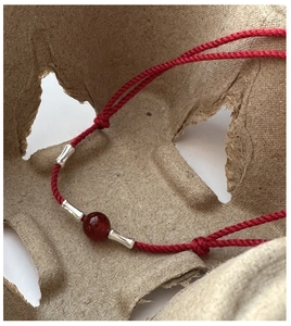 Detail of red woven silk cord with silver bamboo joints and a polished agate bead