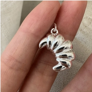 Detailed close-up of a sterling silver croissant pendant with polished mirror finish
