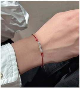 Detailed shot of red cord bracelet with three polished silver cylinders on a woman's wrist