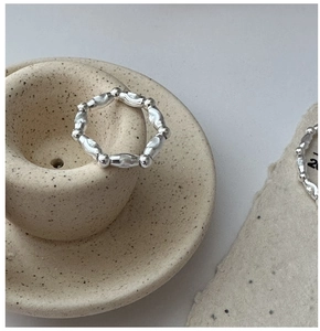 Dettaglio dell'anello a catena in argento S925 con grani intrecciati su ceramica