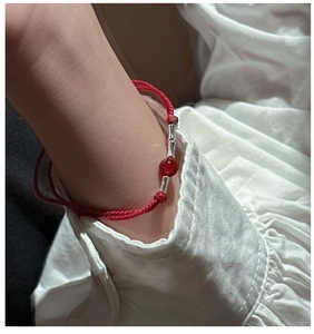 Detail of red braided silver bamboo knot bracelet with agate bead on woman's wrist