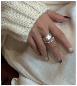 Dettaglio dell'anello in argento S925 martellato e set di perline su maglione bianco