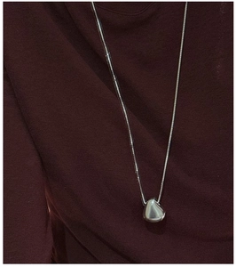 Detail of S925 sterling silver matte organic pendant necklace on red knit sweater