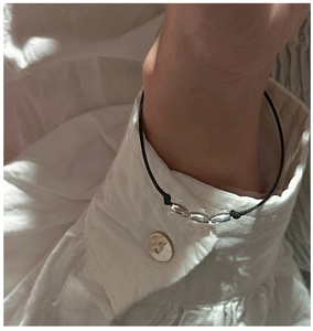 Close-up of minimalist black cord bracelet with three silver beads on a wrist