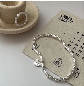 Dettaglio del bracciale e dell'anello con cuore in argento S925 su piatto di ceramica