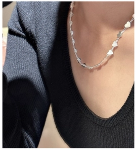 Close-up of S925 sterling silver heart-shaped pendant necklace worn on a black V-neck top