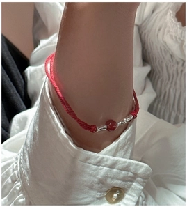 Detailed shot of s925 silver bamboo joints and red agate bead on a braided cord bracelet