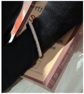 Detail of silver beaded elastic bracelet layered over a black knit sweater cuff