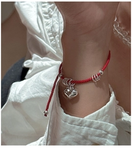Close-up of S925 sterling silver heart charm on red hand-woven adjustable rope bracelet