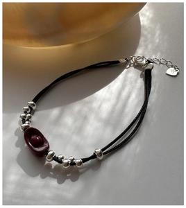 Detailed close-up of S925 silver charm bracelet with red cinnabar ingot on black cord