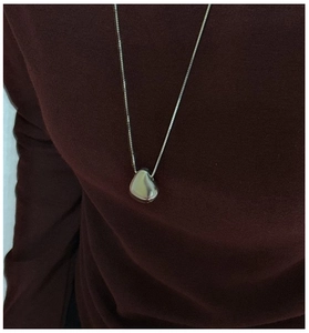 Close-up of minimalist S925 sterling silver bean pendant on a fine silver box chain