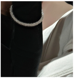 Close-up of woven S925 silver and black beaded bracelet texture on knitwear